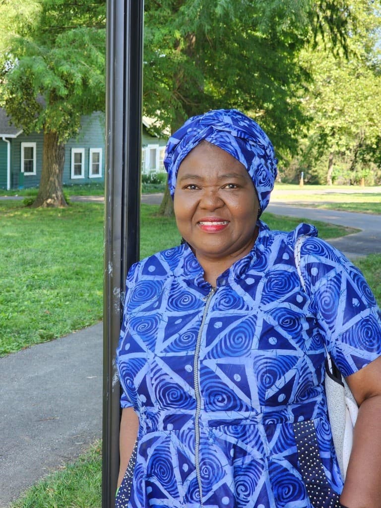 Pastor G.O.A. Okubanjo, convener of Grace Evangelical Fellowship International, smiling outdoors in a blue patterned dress and matching headwrap.